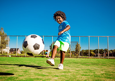Beautiful young black boy training on the football pitch